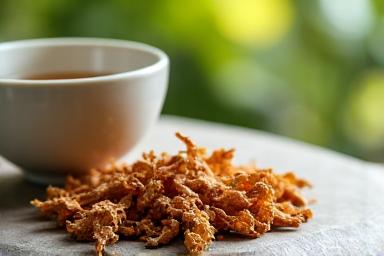 Ginseng roots and adaptogenic herbs neatly arranged on a natural background set alongside a steaming cup of tea, conveying calmness and natural balance.